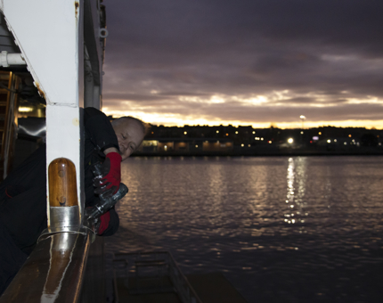 Man holds a drill as he replaces metal guards on Britannia's deck handrail. 