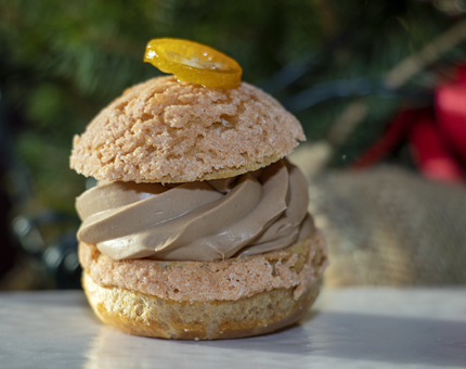 A choux bun containing chocolate cream with clementine on top.