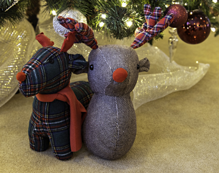 A tartan fabric covered reindeer stop and a tweed fabric covered novelty stag's head underneath the Christmas tree.