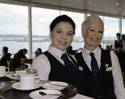 Two waiters in smiling in the Royal Deck Tea Room. 