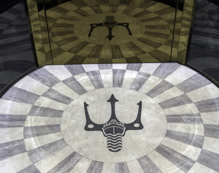 Fingal's trident logo on the floor of the glass lift within the luxury floating hotel. 