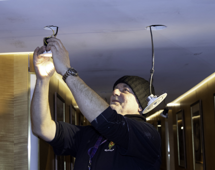 A man removes a light fitting from the ceiling at Fingal.