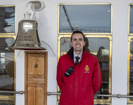 Visitor Assistant stands next to Britannia's Bell. 
