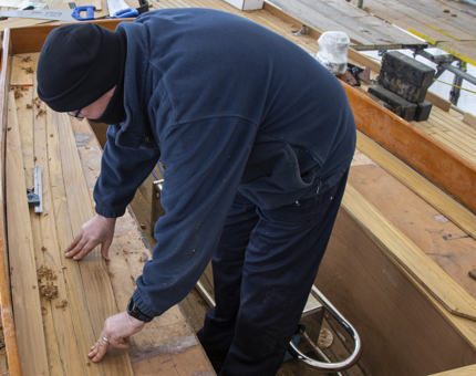 Maintenance man fits deck timbers. 