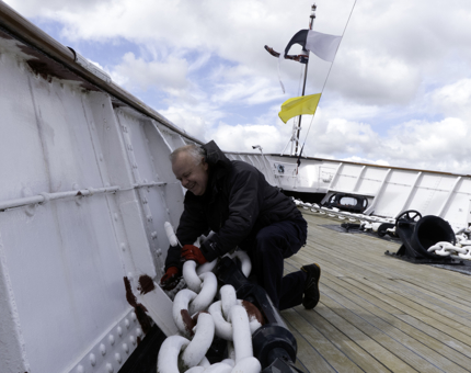 Maintenance team member priming areas of rust on the Foc's'le deck.