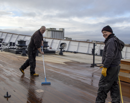 Two members of the Maintenance team scrub the Fo'c'sle Deck.