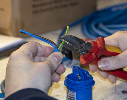 A man holding pliers as he cuts the earth wire for the bespoke extension lead. 
