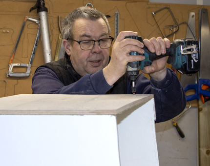 Man from the Maintenance Team making up the box to go around the port hole box in the Junior Rates' Dining Hall. 