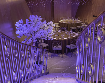 Fingal's Ballroom is beautifully set for an evening event with tables laid and a blossom tree at the foot of the staircase. 