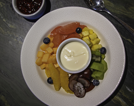 A rainbow coloured fresh fruit platter and yoghurt. 