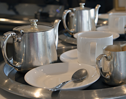 A tray set with a silver teapot, cups and saucers. 
