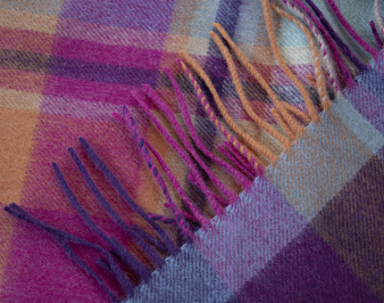 A close-up of a pink, purple and orange tartan scarf. 