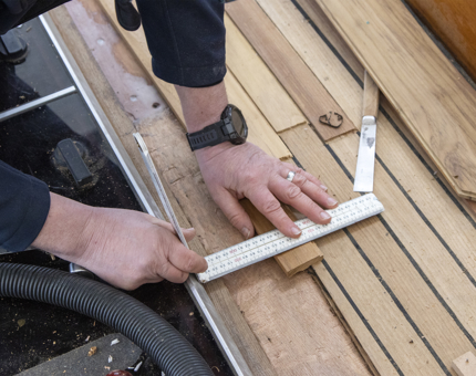 A close-up of a Maintenance team member measuring up to replace deck on Bloodhound.