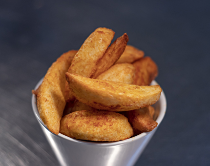 A close-up of a pot of potato wedges. 