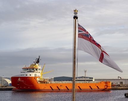 The view out over the Verandah Deck with a ship and a flag fluttering in the wind. 
