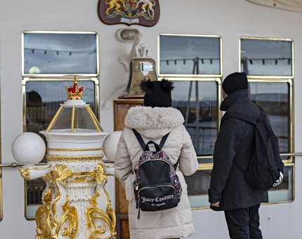 Two visitors wearing winter coats admire the decorative compass binnacle.