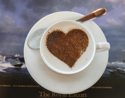 A cappuccino with a chocolate heart-shaped stencil on top. 