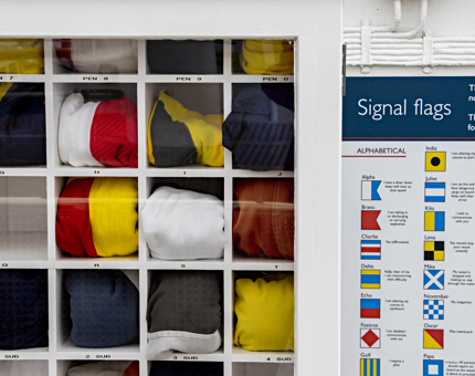 The flag locker of small compartments containing multicoloured rolled-up flags. 