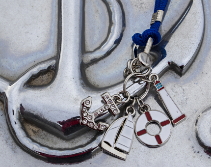 A nautical inspired keyring with charms including a diamante anchor, sailing boat, lifebuoy and lighthouse. 