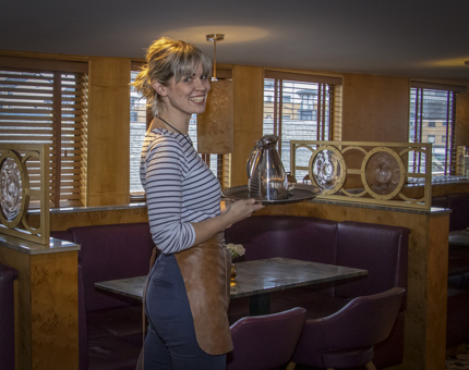 A Waiter holding a silver tray with silver jug of water in Fingal's Lighthouse Restaurant & Bar.