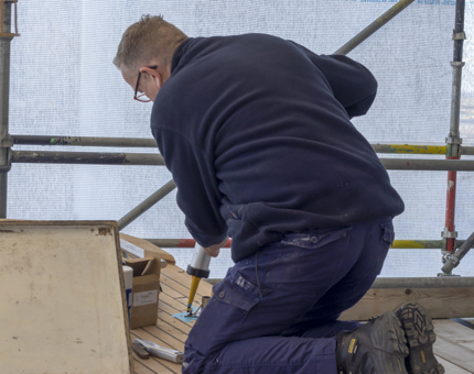 A Maintenance team member holding sealant to fill holes before the bolts are fitted on the deck. 