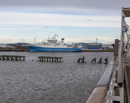 A view from Britannia from deck, over the water with a large blue and white ship in the background. 