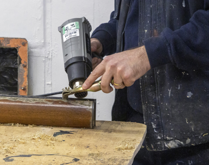A closer look as a member of the Maintenance team holds a tool to strip the varnish. 