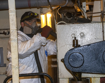 A member of the Maintenance team vacuuming up dust in the Stabiliser Compartment.