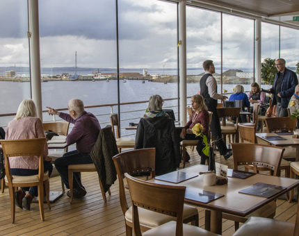 Inside the Royal Deck Tea Room where several visitors are sitting at tables enjoying tea. 