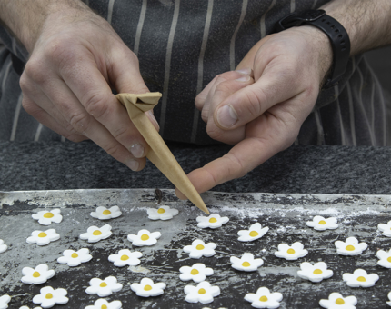 A Chef creating handmade floral decorations for cupcakes. 