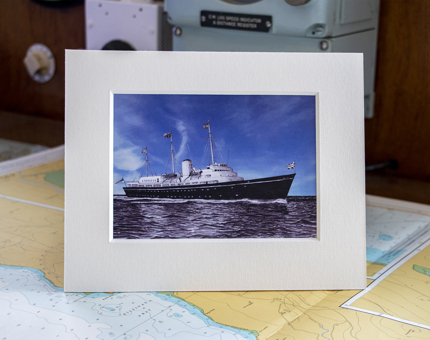 A photograph print of the exterior of The Royal Yacht Britannia sitting on a map. 