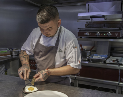 The Breakfast Chef plating up a fried egg in the Galley at Fingal. 
