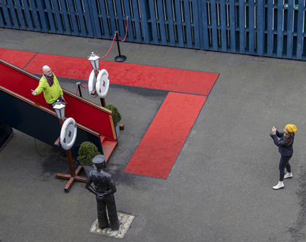 An aerial view of the Royal Brow and red carpet. A visitor is standing on the Royal Brow, posing for a photograph as a woman takes the photo. 