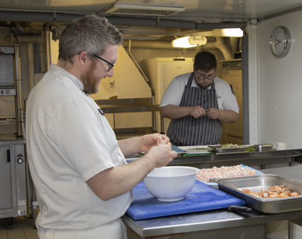 Two chefs preparing langoustines in the Galley. 