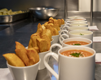 Bowls of potato wedges and mugs of soup are lined up in the Galley.