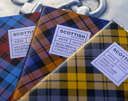 Three bars of chocolate from the Scottish Collection. They each have a different coloured tartan wrapper in blue, orange and yellow. 
