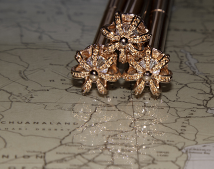 Gold crown-topped pens sit on a map. 