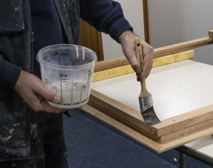 A member of Maintenance painting on varnish to framework.