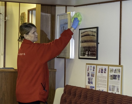 In the Unwinding Room, Housekeeper, Lynn, wiping down the photo frames.