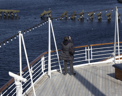 A visitor on the Verandah Deck taking a photograph out across the water.