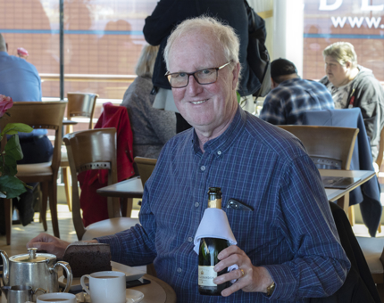 A man celebrating his birthday in the Royal Deck Tea Room with champagne, tea and chocolate cake.