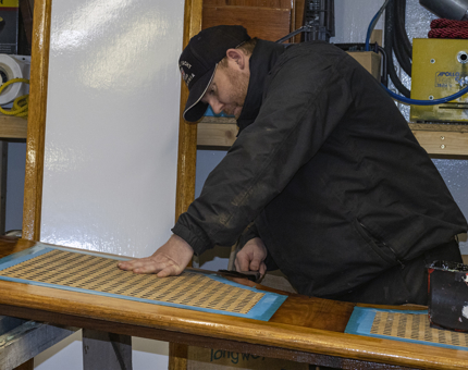 A team member applying varnish to lid of a rope box. 