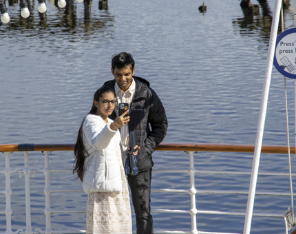 A woman and a man pose together on the Verandah Deck, overlooking the water as they take a selfie photo. 