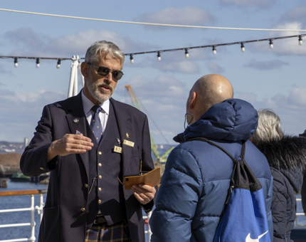 One of the Visitor Assistants is standing outside on deck talking to a visitor. 