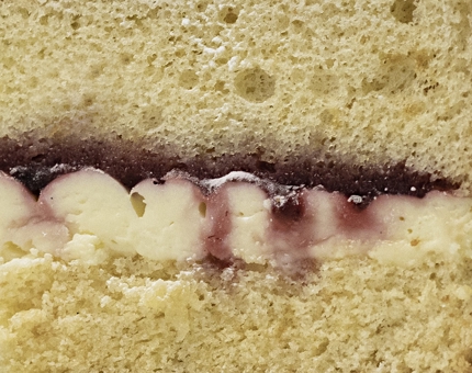 A close-up of the jam and cream filling inside a slice of Victoria sponge cake. 
