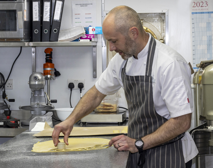 The Executive Pastry Chef cutting out shortbread rounds in the Galley. 