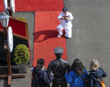 A Yottie takes a photograph of visitors next to the statue of Ellis Victor ‘Norrie’ Norrell MVO RVM, Britannia's longest serving Yachtsmen. 