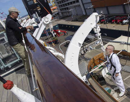 A visitor chatting to a Yottie who is working on one of the Jolly Boats.