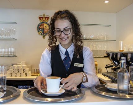 A member of the Tea Room staff preparing a coffee behind the bar. 