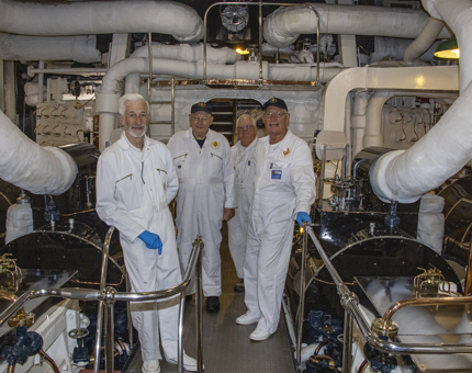 Yotties pose for a photograph wearing their white overalls in the Engine Room. 